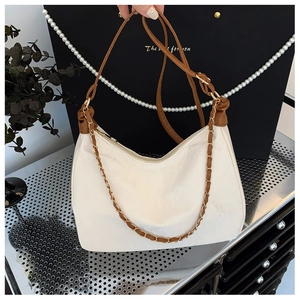 Détail d'un sac hobo avec bandoulière en cuir marron et chaîne décorative en métal