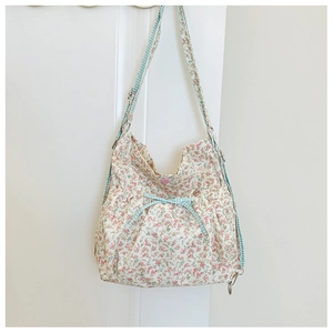 Macro detail of floral canvas bag with light blue plaid strap and bow decoration