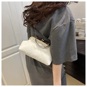 Detail of white embroidered fabric handbag with luxury gold handle and metal clasp closure