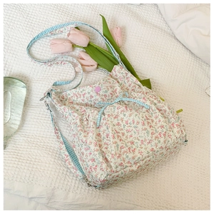 Floral canvas bag detail with pink flower pattern and blue checkered strap on white cloth