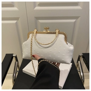Detail of white vintage frame bag with textured fabric, gold metal handle and chain
