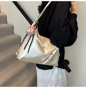 Close-up of champagne gold Hobo bag with plush monkey charm on leather side