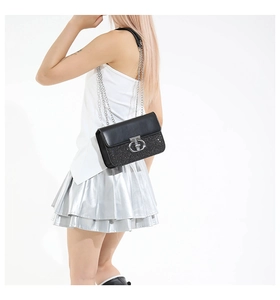 Detail of black sequined crossbody bag with silver chain strap and metallic rotary lock