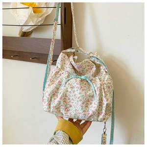 Detail of floral fabric crossbody bag with blue gingham bow and pink magnetic closure