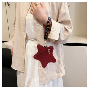 Close-up of star-shaped red pebble leather coin purse with colorful woven wristlet strap
