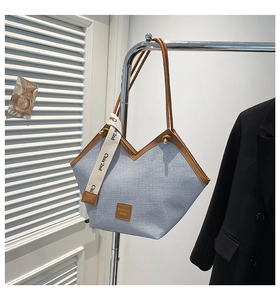 Detail der blauen Denim-Tragetasche mit braunen Griffen und stylischem Band mit Schriftzug