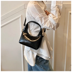 Detail of black glossy crescent shoulder bag with pearl charm and adjustable strap