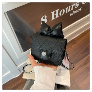 Close-up of black quilted mini crossbody bag with a large bow and silver camellia clasp
