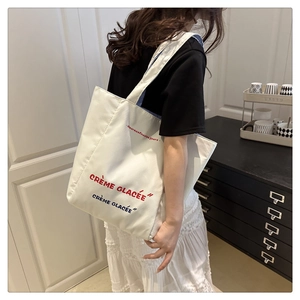Detailed shot of an off-white canvas tote bag with French letters and striped lining