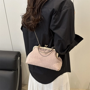 Pink fabric frame bag with gold chain and round handle, shown as a crossbody wear