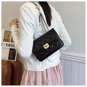 Detail of black quilted leather shoulder bag with gold metal clasp and chain strap