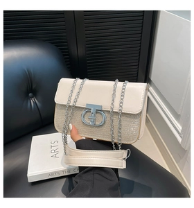 Detail of a beige chain bag featuring shimmering sequins and a metallic CD twist lock