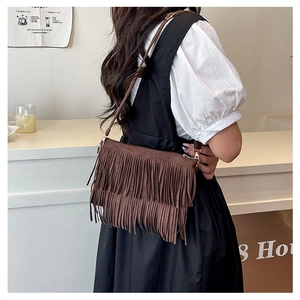 Détail d'un sac à bandoulière marron à franges avec un design bohème et boucles dorées