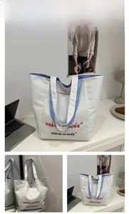 Detailed shot of white canvas tote bag with Crème Glacée lettering and blue striped handles