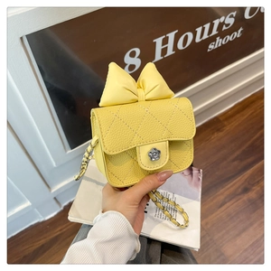 Close-up of bright yellow quilted crossbody bag with large bow and floral metal clasp