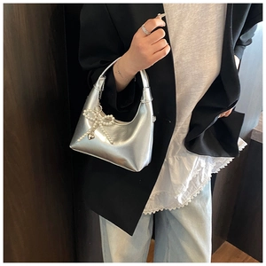 Close-up of a silver metallic hobo bag with a pearl bow charm and heart detail