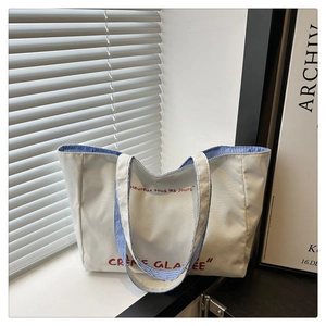 Detail of white canvas tote bag with red lettering and blue striped lining in sunlight