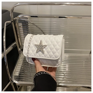 Détail macro du sac blanc matelassé avec étoile en strass et bandoulière en chaîne