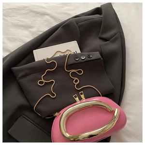 Detail of pink patent leather handbag featuring distinctive oversized gold metal handles