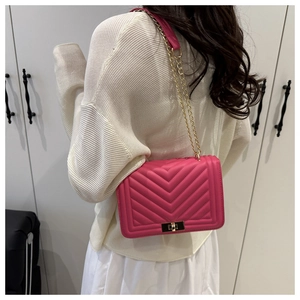 Detail of rose red chevron quilted leather bag with elegant gold chain strap and turn-lock