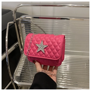 Gros plan sur un sac bandoulière rose matelassé avec étoile en strass et chaîne argent