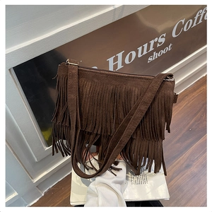 Détail du sac à bandoulière en daim marron foncé avec pompons à franges style bohème