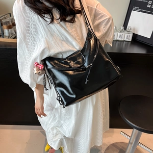 Glossy black versatile shoulder bag for women with a plush pendant charm in a shop