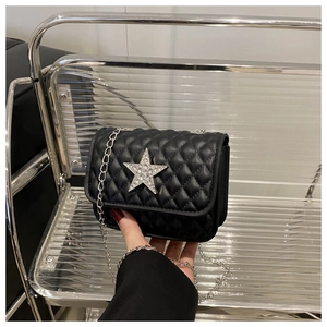 Détail d'un petit sac matelassé noir avec une étoile scintillante en strass argentés