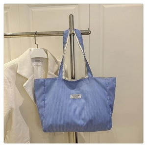 Detail of blue striped canvas tote bag featuring Fashion Instinct embroidery label