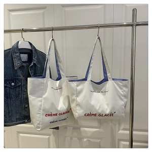 Close-up of dual-style canvas tote bags with blue striped lining and red text detail