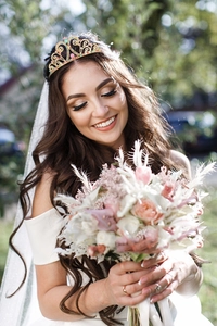 Close-up of a colorful crystal bridal tiara with golden filigree on a smiling model