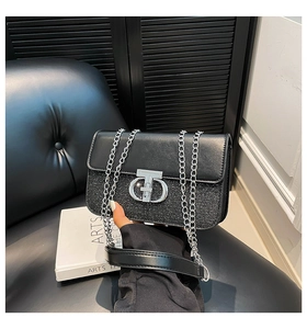 Close-up of black sequin shoulder bag with leather flap and silver chain link strap