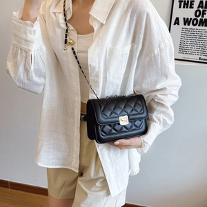 Chic black quilted chain shoulder bag with gold clasp shown on a white shirt model