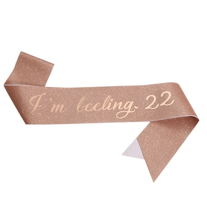 Dettaglio fascia glitter oro rosa con elegante scritta corsiva I'm feeling 22