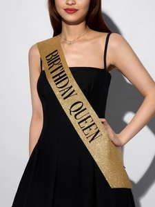 Detail of glitter gold sash with black Birthday Queen text worn by a model in a dress
