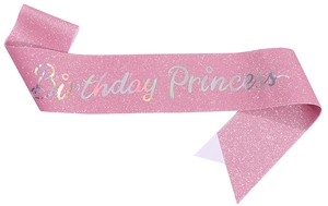 Close-up of pink glittery sash with holographic Birthday Princess text on white background