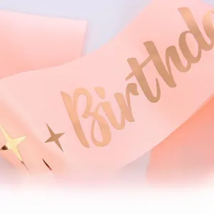 Gros plan de l'écharpe d'anniversaire en satin rose avec étoiles et lettrage dorés