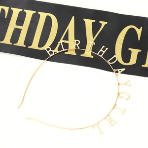 Close-up of golden Birthday Girl metal headband and black satin sash for party
