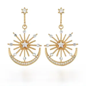 Close-up of golden celestial sun and moon drop earrings with clear sparkling rhinestones