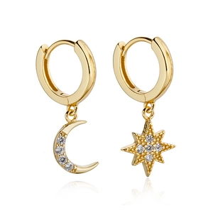 Macro shot of asymmetric gold-tone hoop earrings with rhinestone moon and star charms