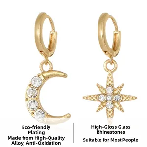 Detail view of gold-plated star and moon earrings with shiny glass rhinestones