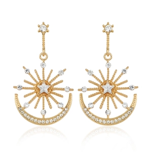 Detail of celestial gold earrings featuring star rays and crystal-encrusted crescents