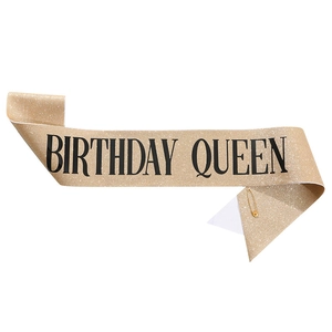 Glittering gold Birthday Queen sash with black serif lettering and gold safety pin