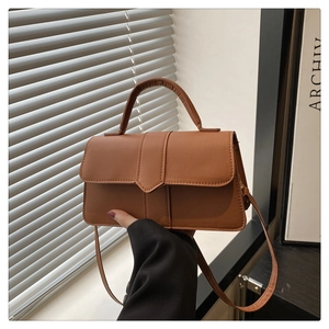 Detailaufnahme einer karamellbraunen Baguette-Tasche aus Leder mit Klappe und Griff