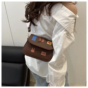Detail of vintage brown shoulder bag with colorful art patches on the textured surface
