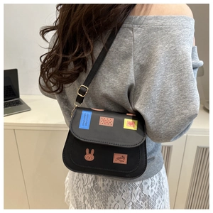 Detail of black leather crossbody bag featuring cute rabbit patches and heart motifs