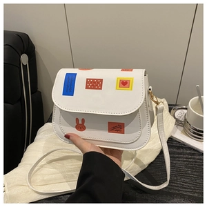 Détail d'un sac à bandoulière blanc avec imprimés lapin et écussons colorés de style