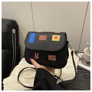 Détail du sac noir en similicuir avec écussons colorés de lapin et de cœur mignons