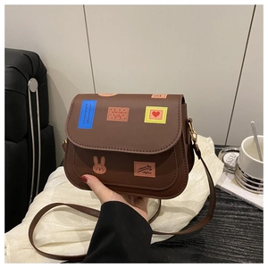 Gros plan d'un sac à bandoulière marron vintage avec imprimés timbres et cuir lisse