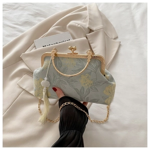 Detailed close-up of floral fabric handbag with metal frame handle and tassel decoration